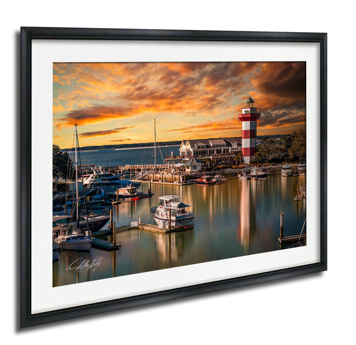 a serene harbor scene at sunset, with boats docked in the calm waters and a lighthouse standing tall in the background.