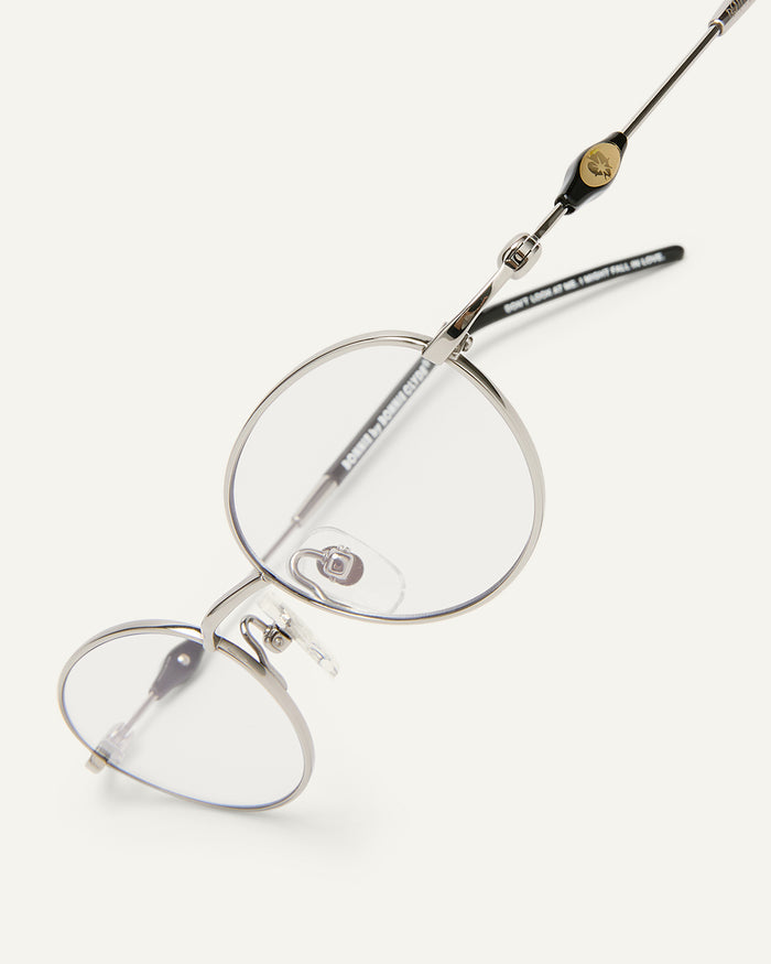 Side shot of Bonnie Clyde Heirloom optical frames in silver and black with clear lenses.