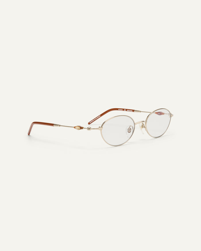 Close-up shot of Bonnie Clyde Heirloom optical frames in gold and dark brown with clear lenses.