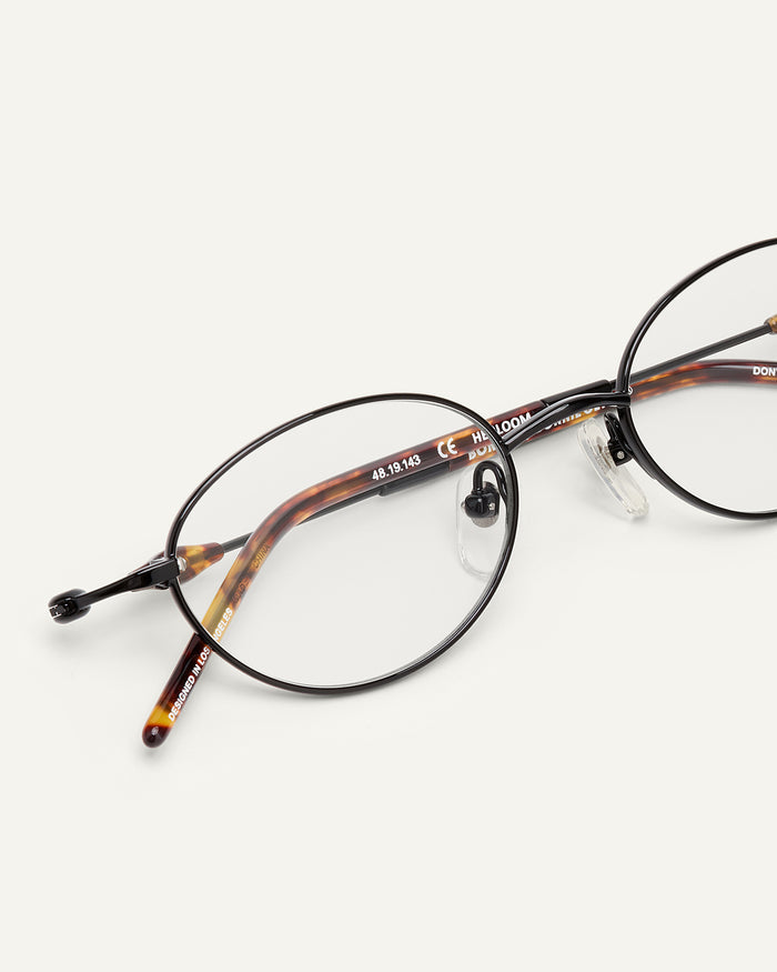 Close-up shot of Bonnie Clyde Heirloom optical frames in black and tortoise with clear lenses.