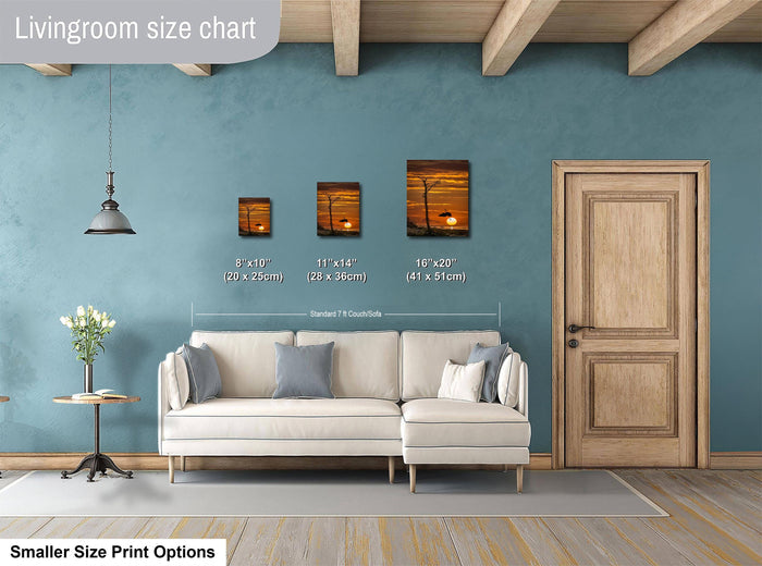a living room with a white sofa, a wooden door, and a painting on the wall. The painting is of a sunset, and the sofa is positioned in front of it. The living room appears to be well-lit and decorated.