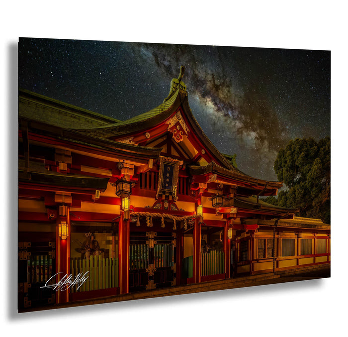 A traditional Japanese temple with a red roof and intricate decorations, illuminated at night against a starry sky.