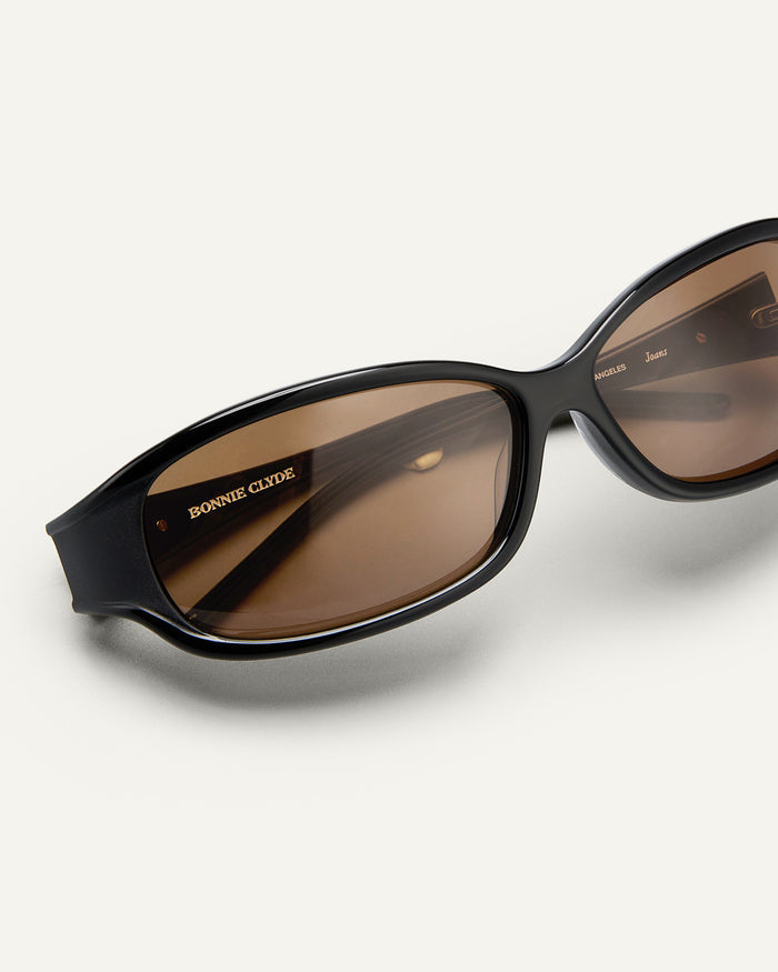 Detail shot of Bonnie Clyde Joans sunglasses in black with brown lenses.