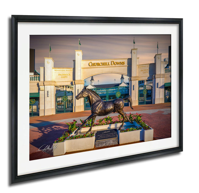 A bronze statue of a horse stands in front of the entrance to the Churchill Downs racetrack, with the words "Churchill Downs" displayed above the entrance.