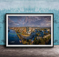 The image is a framed aerial view of a cityscape, showcasing a mix of buildings, roads, and a river.
