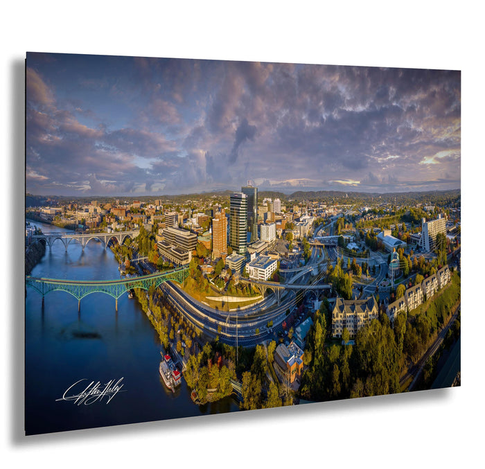 The image is an aerial view of a city with a river running through it, featuring a bridge and various buildings.