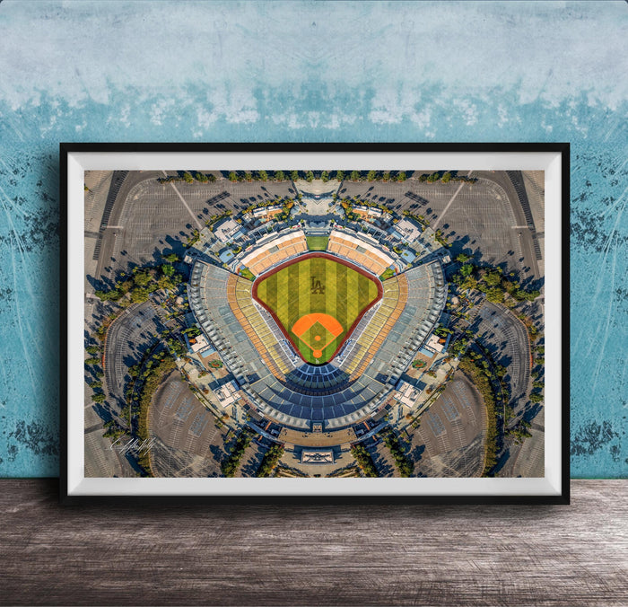 The image is an aerial view of a baseball stadium, featuring a large field surrounded by parking lots and other structures.