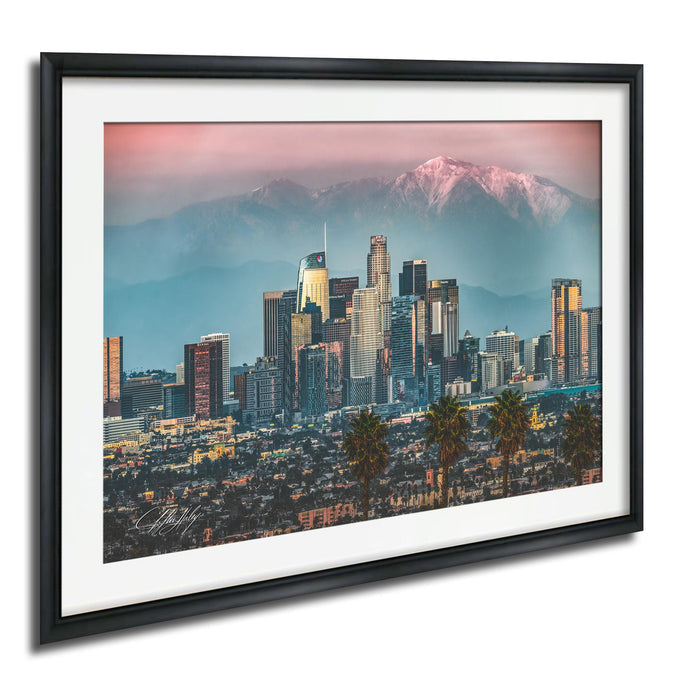 A framed photograph of the Los Angeles skyline at sunset, with the city's skyscrapers and mountains in the background.