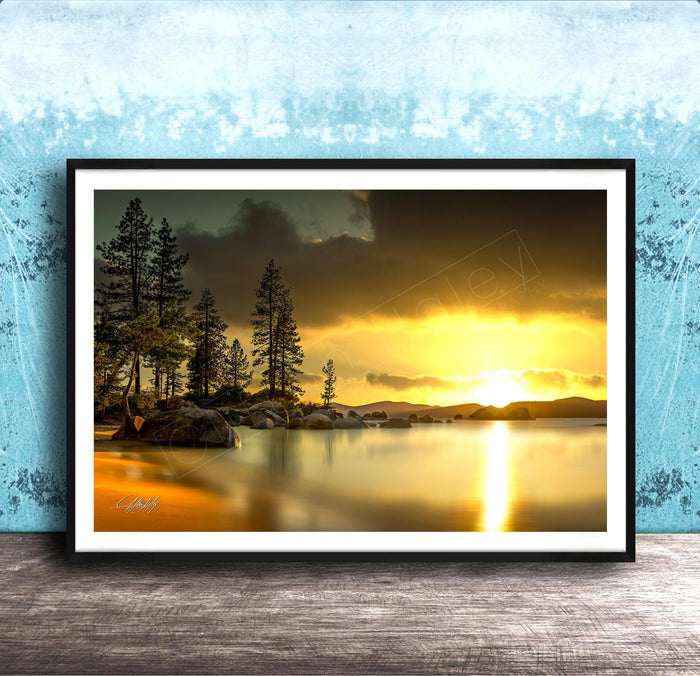 A framed photograph depicting a serene landscape with a lake, trees, and a sunset over the water.