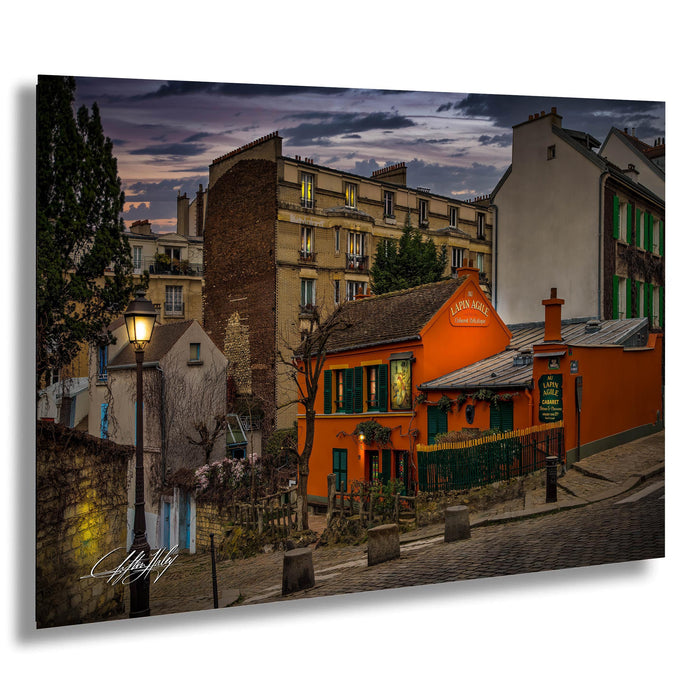 a charming street scene in a European city at dusk, with colorful buildings, a restaurant, and a lamppost.