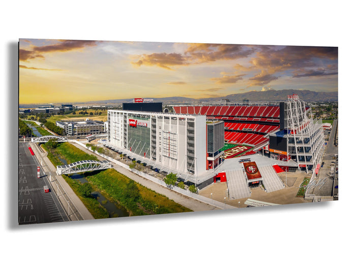 a large stadium with a red roof and white walls, surrounded by a large parking lot and a bridge. The stadium appears to be a sports venue, possibly a professional sports stadium.