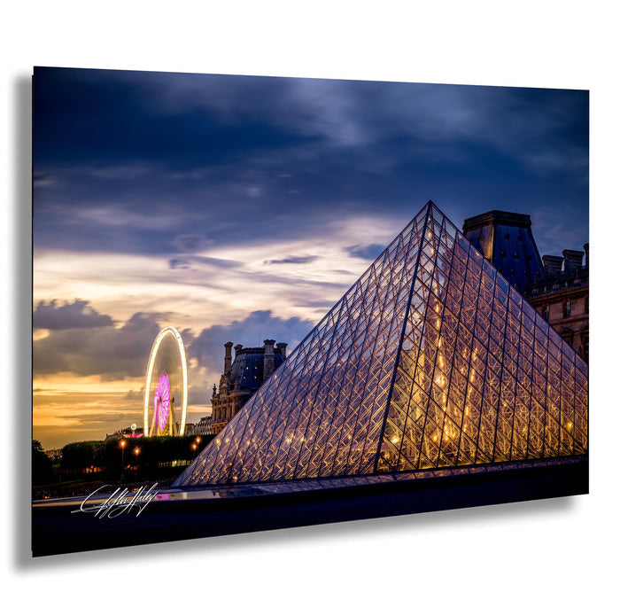 a large glass pyramid structure with a ferris wheel in the background, set against a colorful sunset sky.