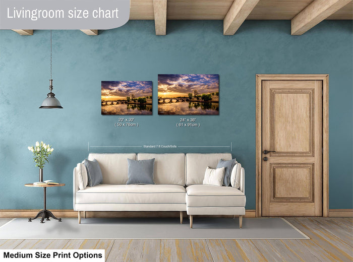a living room with a white sofa, a wooden door, and a painting of a scenic landscape on the wall. The painting is of a bridge and a lake, and it is of medium size. The living room has a blue wall and a wooden floor.