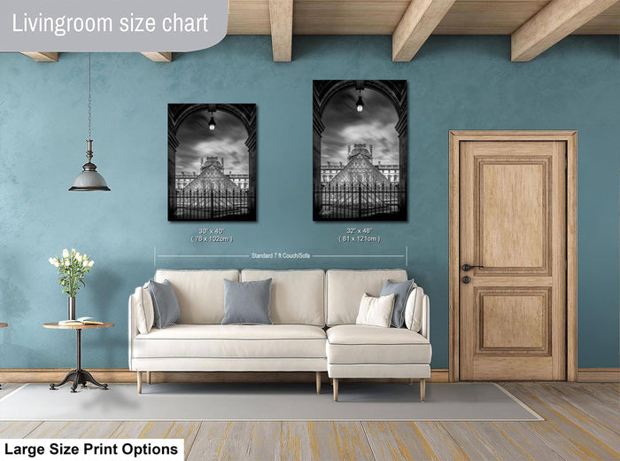 a living room with a white sofa, a wooden door, and two framed black and white photographs of a building, likely a cathedral, hanging on the wall.