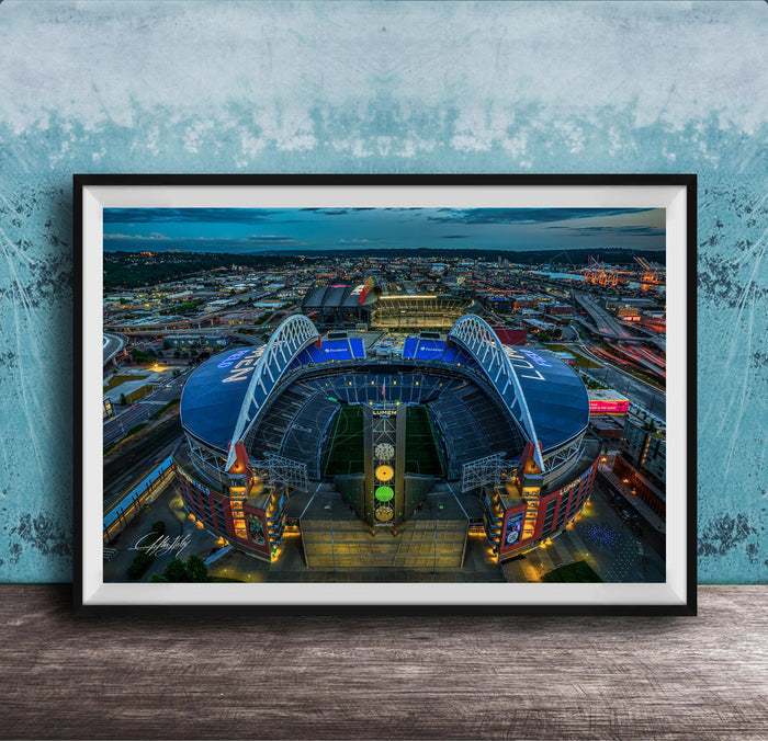 The image is a framed photograph of a large stadium at night, with the stadium's lights illuminating the surrounding cityscape.