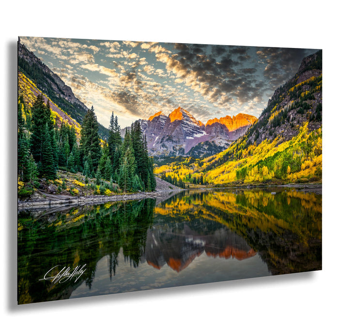a serene mountain landscape with a calm lake reflecting the vibrant colors of the surrounding trees and mountains.