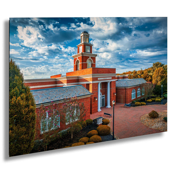 a red brick building with a prominent clock tower, surrounded by trees and a brick walkway.