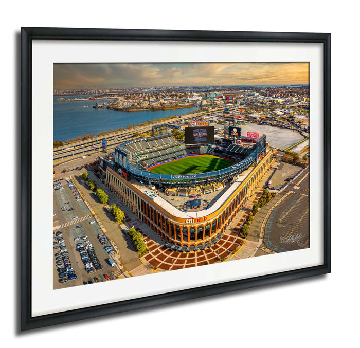 The image is an aerial view of a baseball stadium with a large field, surrounded by a cityscape.