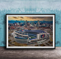 The image is an aerial view of a large sports stadium, likely a football stadium, with the city skyline in the background.