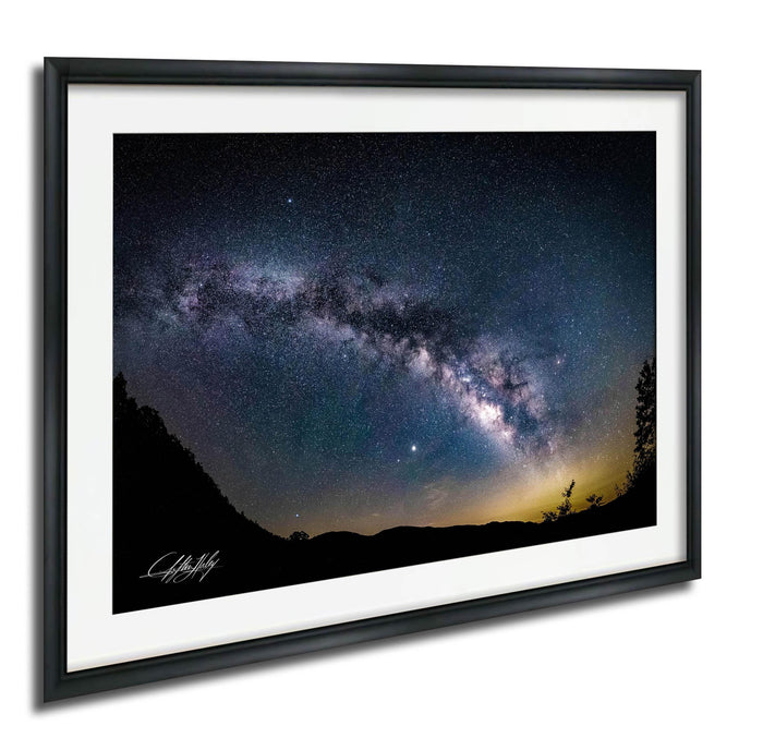 a stunning night sky with a galaxy and stars, framed in a black frame and hung on a wall.