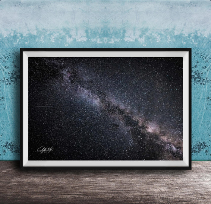 The image is a framed photograph of the night sky, depicting a vast, starry galaxy.