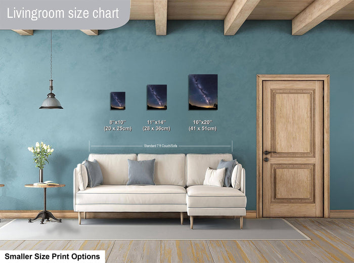 a living room with a white sofa, a wooden door, and a hanging light fixture. There are three framed pictures of the night sky displayed on the wall, each with a different size and resolution. The living room appears to be designed for relaxation and comfort, with a focus on the artwork and the overall aesthetic.