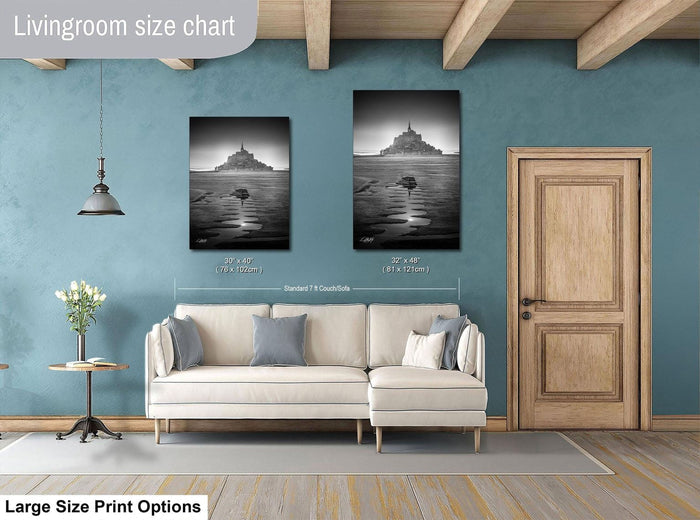 a living room with a white sofa, a wooden door, and two framed black and white photographs hanging on the wall.