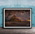 A framed photograph of the iconic Mont Saint-Michel in Normandy, France, with a dramatic sky in the background.