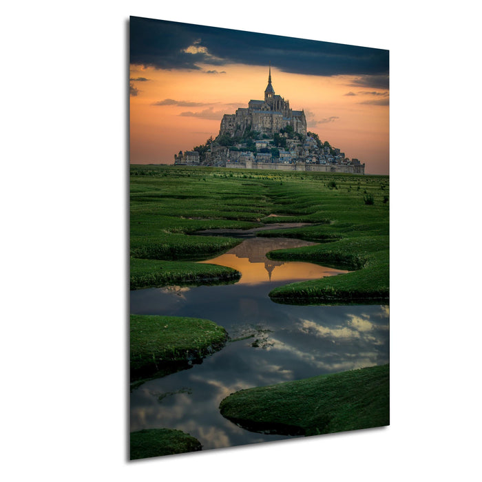 a large castle or palace situated on a hill, with a body of water or lake in the foreground. The sky is filled with clouds, creating a dramatic backdrop for the scene. The castle appears to be made of stone and is surrounded by a moat or lake, which adds to the picturesque setting. The overall composition of the image is balanced and visually appealing, with the castle and its surroundings creating a sense of grandeur and majesty.