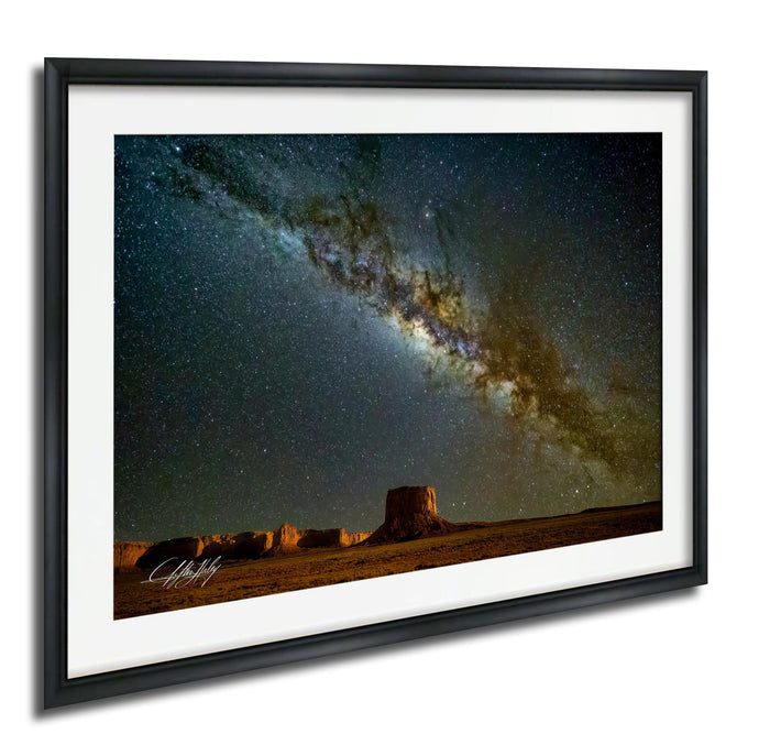 a desert landscape at night, with a starry sky and a large sand formation in the foreground.