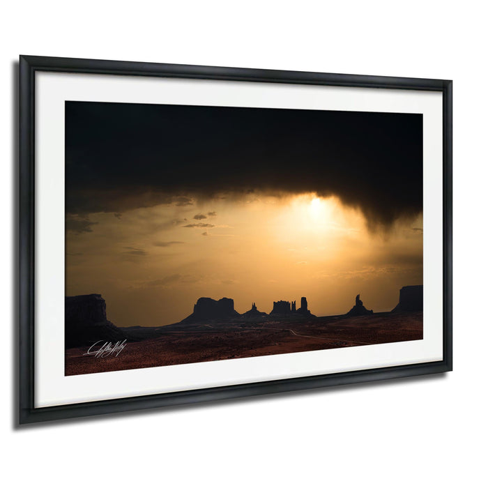 a dramatic sunset over a desert landscape, with silhouetted mountains in the background.