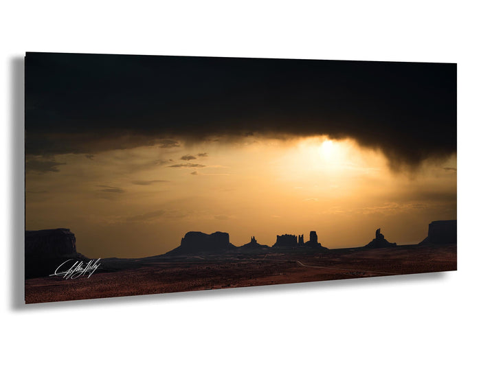 a dramatic sunset over a desert landscape, with silhouetted mountains in the background and a dramatic cloud formation in the sky.