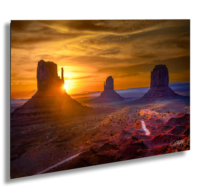 a breathtaking desert landscape at sunset, with three large rock formations silhouetted against the vibrant orange and yellow sky.