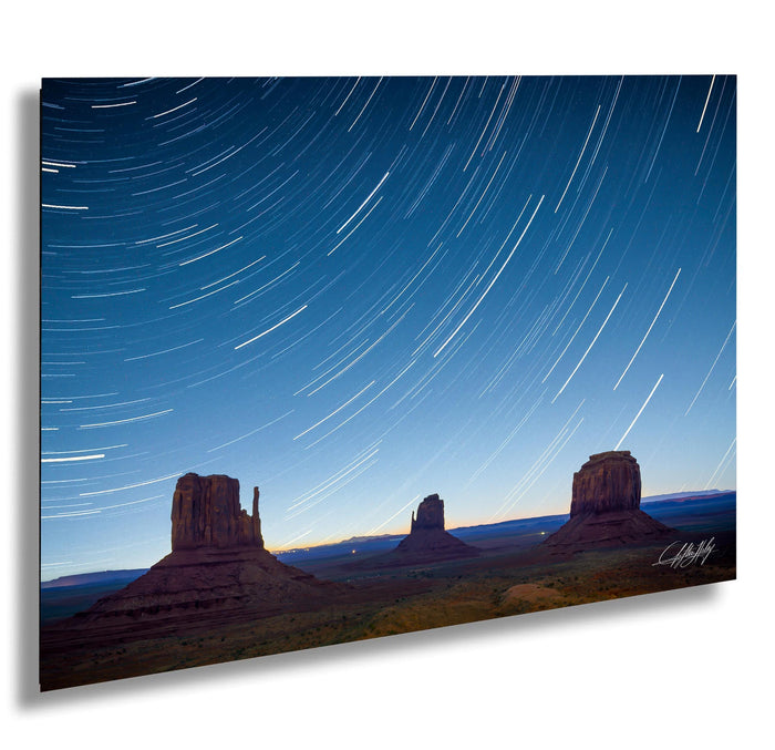 A stunning night landscape featuring three iconic rock formations silhouetted against a starry sky, with a trail of light streaking across the sky.