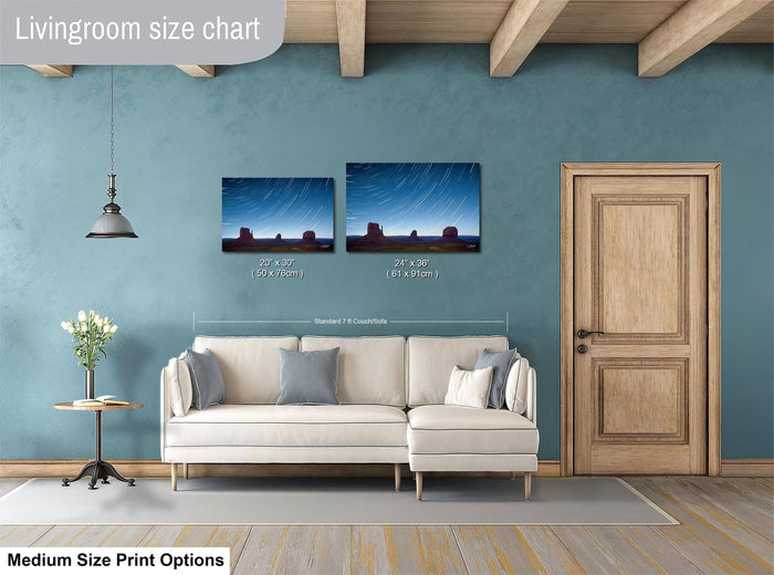 a living room with a white sofa, a wooden door, and a painting of a desert landscape on the wall. The living room appears to be well-lit and decorated with a potted plant and a vase.