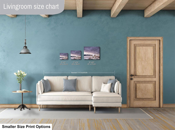 a living room with a white sofa, a wooden door, and a hanging light fixture. There are three framed artworks displayed on the wall above the sofa, each with a different size and frame. The living room appears to be well-decorated and spacious.