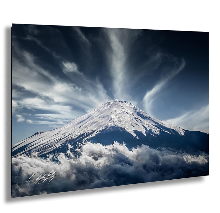 A majestic snow-capped mountain peak rises above a dramatic sky filled with clouds, creating a breathtaking natural landscape.