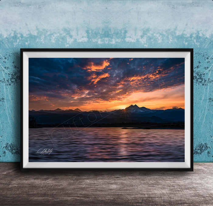 a breathtaking sunset over a mountain range, with the sun setting behind the peaks and casting a warm, golden glow across the sky.