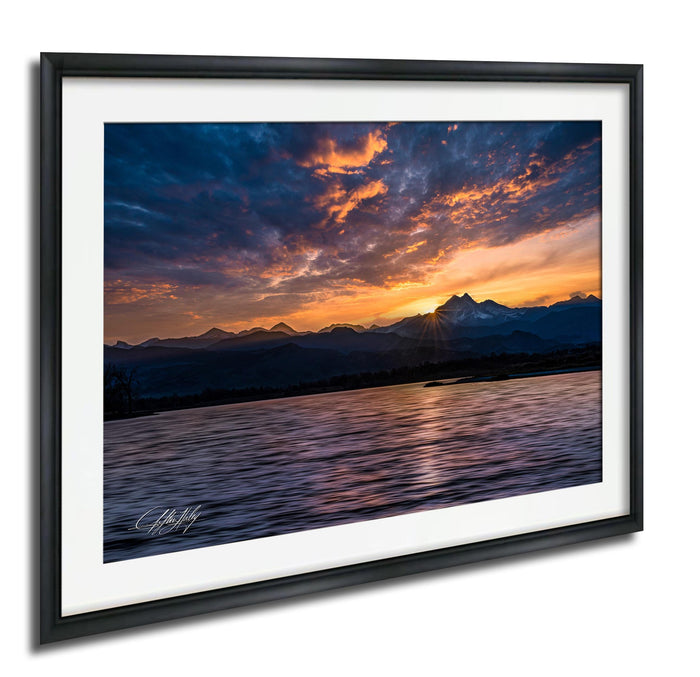 a breathtaking sunset over a mountain range, with the sun setting behind the peaks and casting a warm, golden glow across the sky.