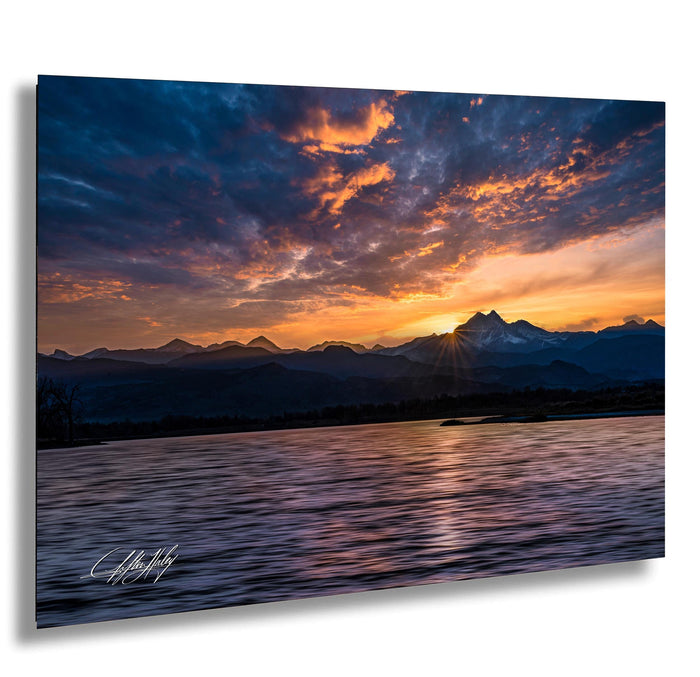 a breathtaking sunset over a mountain range, with the sun's rays reflecting off the calm waters below.