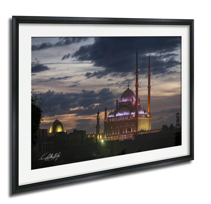 a large mosque with illuminated domes and minarets, set against a dramatic sky at dusk.