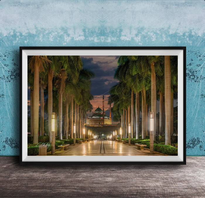 A framed photograph depicting a serene nighttime scene of a palm-lined walkway leading to a building, with the sky illuminated by the warm glow of the setting sun.