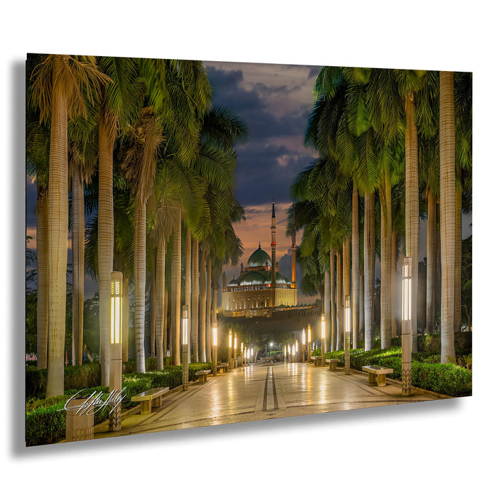 A serene night scene of a palm-lined pathway leading to a mosque, with the mosque's dome and minaret visible in the distance.