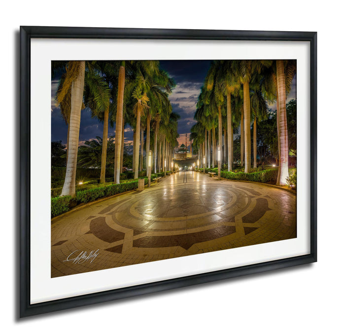 A well-lit, circular walkway lined with palm trees at night, creating a serene and inviting atmosphere.