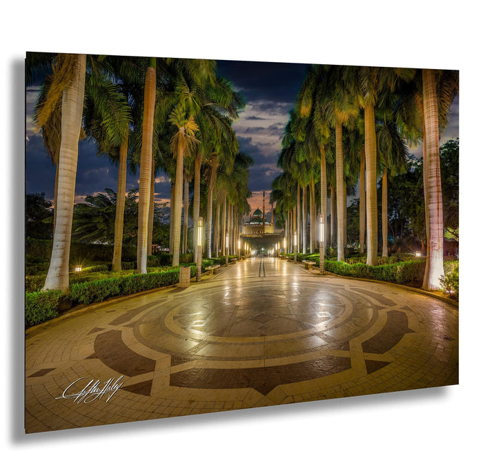A well-lit, circular walkway lined with palm trees and illuminated by warm lighting, creating a serene and inviting atmosphere.
