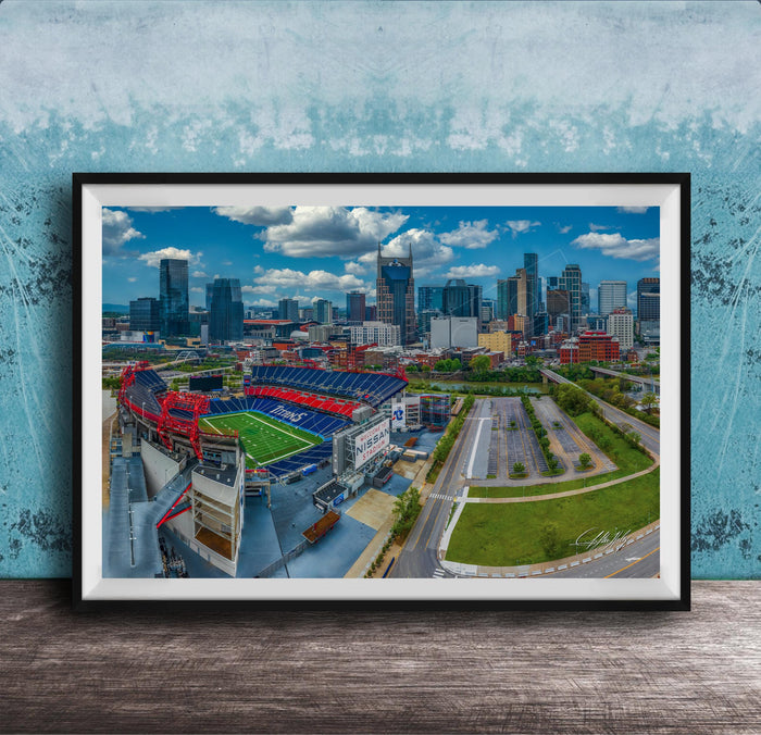 The image is an aerial view of a city skyline, featuring tall buildings and a large sports stadium with a red roof.