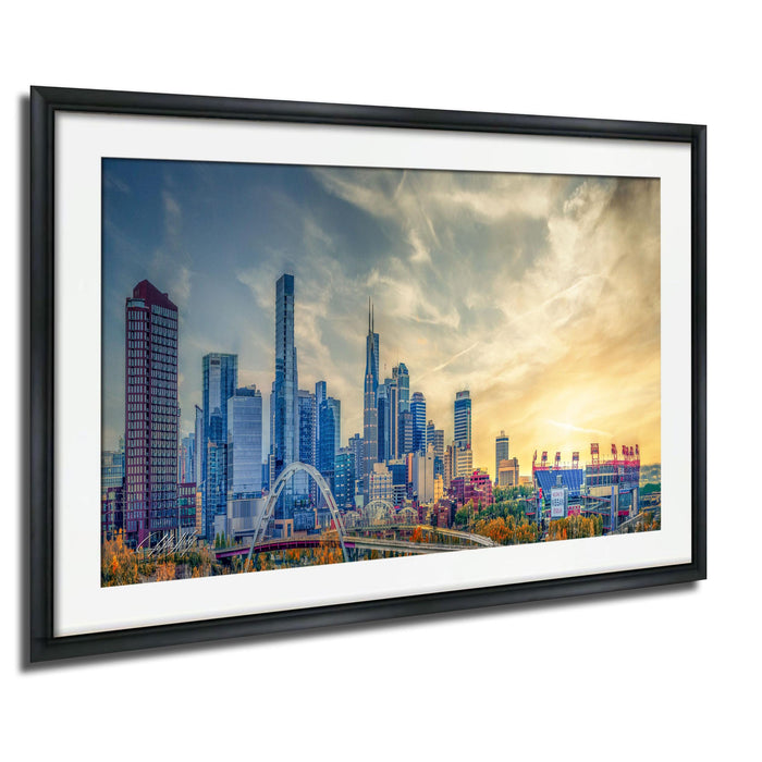 The image is a framed photograph of a city skyline, featuring a mix of tall buildings and skyscrapers against a colorful sky.