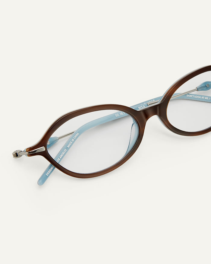 Side shot of Bonnie Clyde Nisa optical frames in silver and layered teal demi with clear lenses.