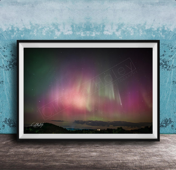 The image is a framed photograph of a night sky with the aurora borealis, or northern lights, visible.