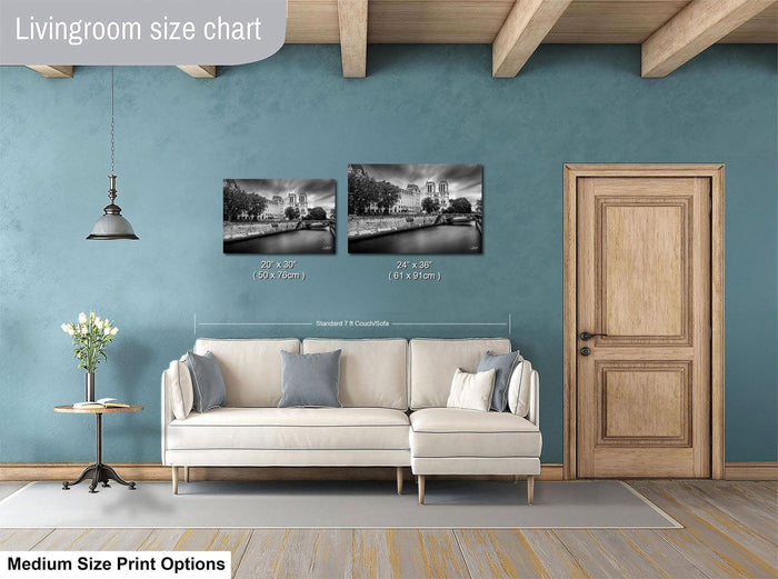 a living room with a white sofa, a wooden door, and a hanging light fixture. There are two black and white photographs of a cityscape displayed on the wall above the sofa.